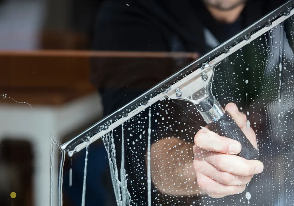 Femme blonde en manteau beige contemplant une vitrine de magasin de vêtements dans un centre commercial